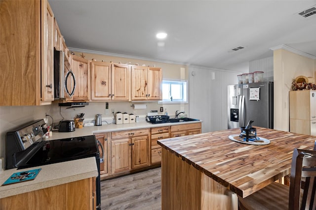 kitchen with stainless steel appliances, ornamental molding, light brown cabinetry, and light wood-type flooring