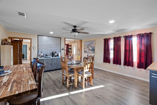 dining space with hardwood / wood-style floors, crown molding, and ceiling fan