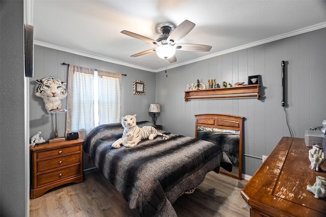 bedroom with ornamental molding, wooden walls, hardwood / wood-style floors, and ceiling fan