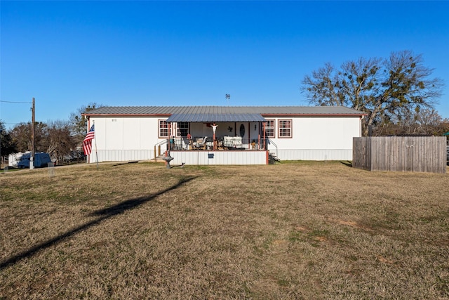 back of property with covered porch and a yard