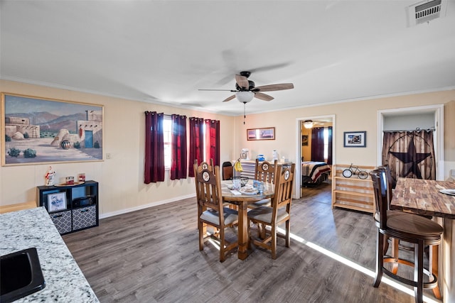 dining area featuring baseboards, visible vents, ceiling fan, dark wood-style flooring, and crown molding