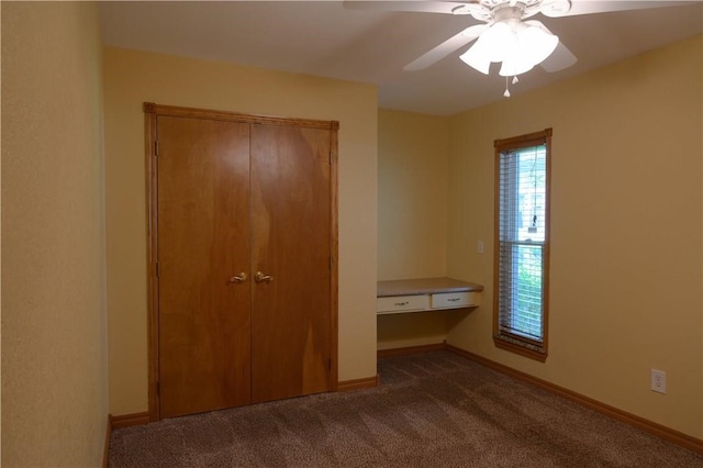 unfurnished bedroom with ceiling fan, a closet, and dark carpet