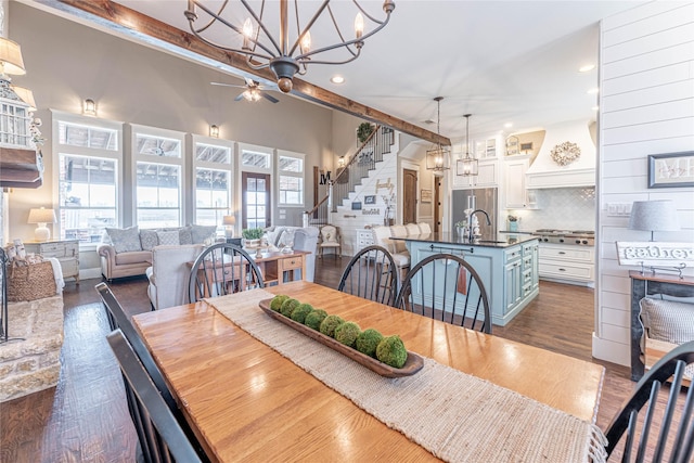 dining space with beamed ceiling, ceiling fan with notable chandelier, dark hardwood / wood-style floors, and sink