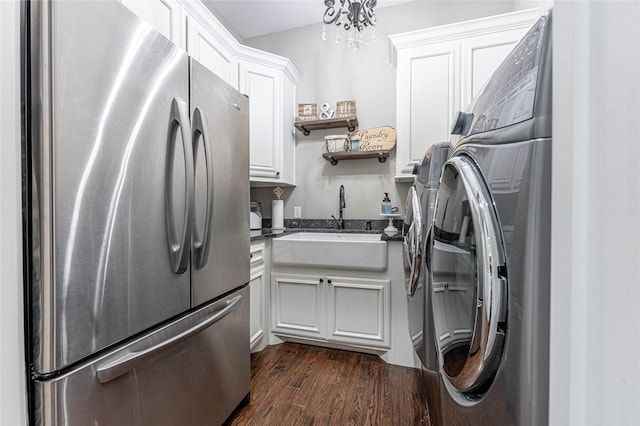 kitchen with white cabinets, stainless steel fridge, washer and clothes dryer, and sink