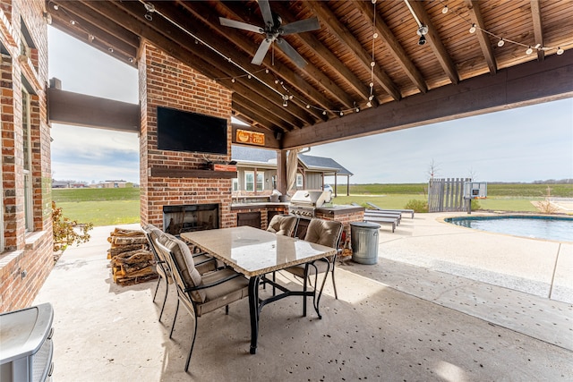 view of patio featuring a grill, ceiling fan, exterior kitchen, and an outdoor brick fireplace