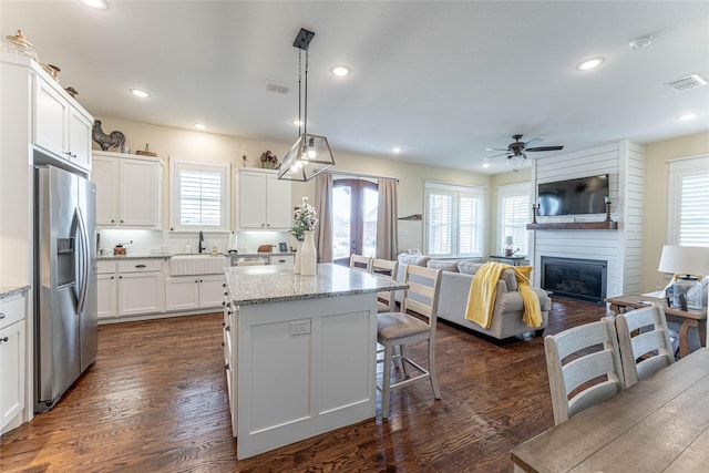 kitchen with decorative light fixtures, white cabinetry, light stone countertops, and stainless steel fridge with ice dispenser