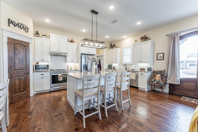 kitchen with pendant lighting, a center island, white cabinetry, and stainless steel appliances