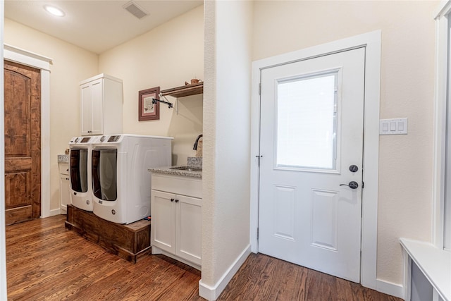 clothes washing area with cabinets, dark hardwood / wood-style flooring, sink, and washing machine and clothes dryer