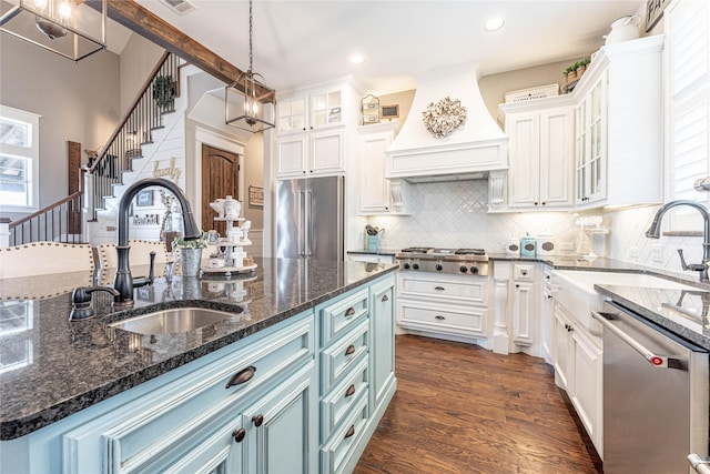 kitchen featuring sink, appliances with stainless steel finishes, a kitchen island with sink, white cabinets, and custom exhaust hood