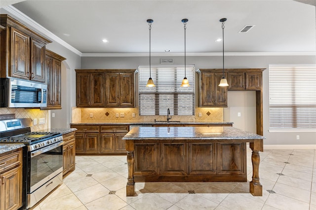 kitchen with a center island, stone counters, appliances with stainless steel finishes, tasteful backsplash, and decorative light fixtures