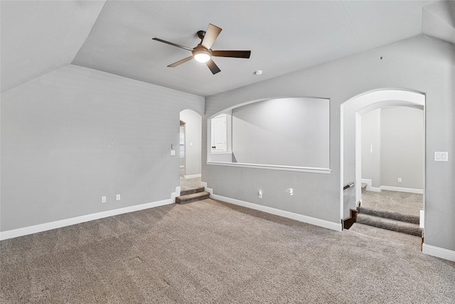 carpeted spare room featuring vaulted ceiling and ceiling fan