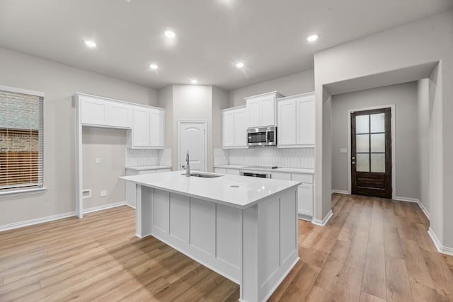 kitchen featuring stainless steel microwave, a sink, decorative backsplash, and light countertops
