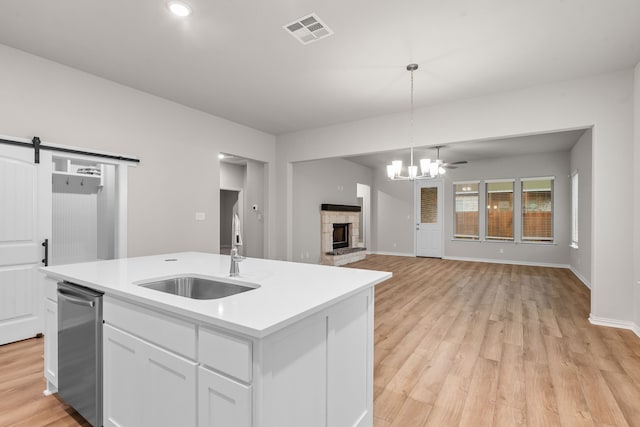 kitchen featuring a sink, a fireplace, visible vents, light countertops, and white cabinets