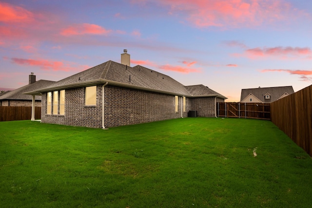 back of house with a chimney, a fenced backyard, central AC, and a lawn