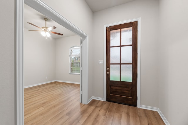 doorway featuring light wood-style floors, ceiling fan, and baseboards