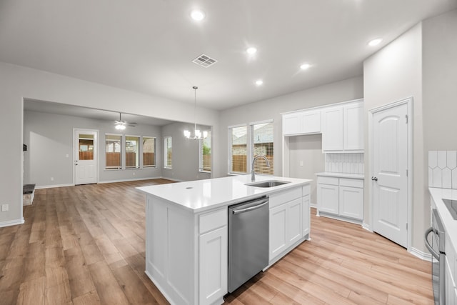 kitchen with light countertops, stainless steel dishwasher, light wood finished floors, and a sink