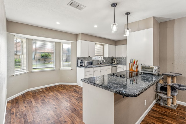 kitchen featuring kitchen peninsula, backsplash, black electric cooktop, dark stone countertops, and white cabinets