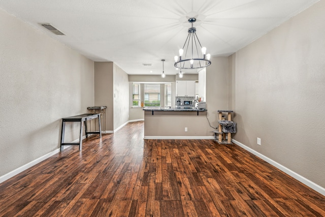 kitchen with kitchen peninsula, hanging light fixtures, a notable chandelier, dark hardwood / wood-style flooring, and white cabinetry