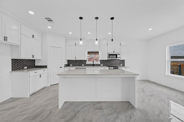 kitchen with white cabinetry, appliances with stainless steel finishes, a center island, and hanging light fixtures