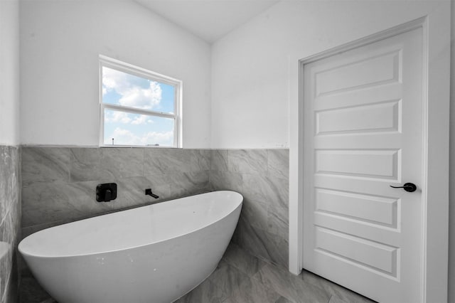 bathroom with a tub and tile walls