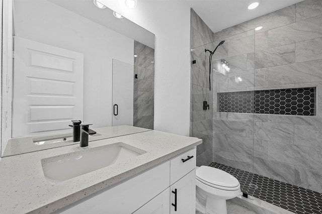 bathroom with vanity, toilet, and tiled shower