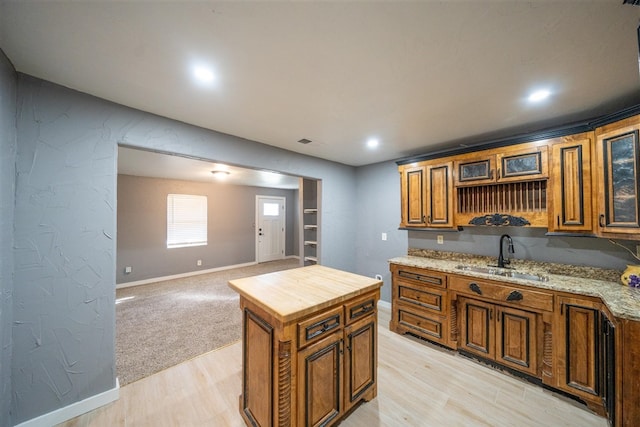 kitchen featuring light stone countertops, light wood-type flooring, a kitchen island, and sink