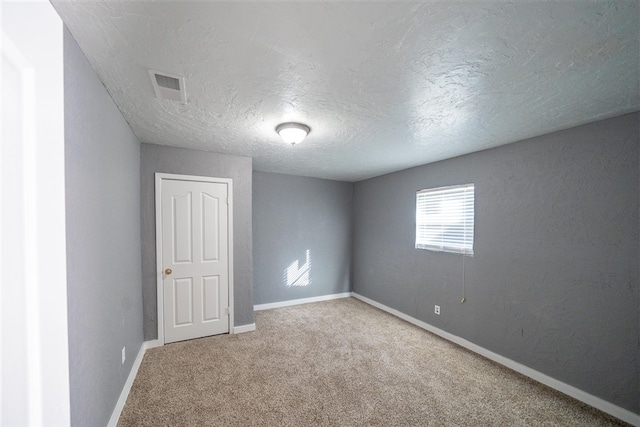 spare room featuring carpet flooring and a textured ceiling