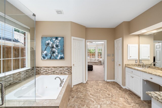 bathroom with vanity and tiled bath