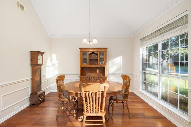 dining area featuring lofted ceiling, dark hardwood / wood-style flooring, an inviting chandelier, and ornamental molding