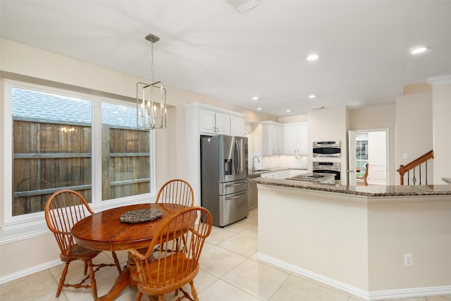 kitchen with appliances with stainless steel finishes, tasteful backsplash, dark stone countertops, white cabinetry, and light tile patterned flooring