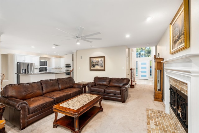 living room with light colored carpet, a brick fireplace, and ceiling fan