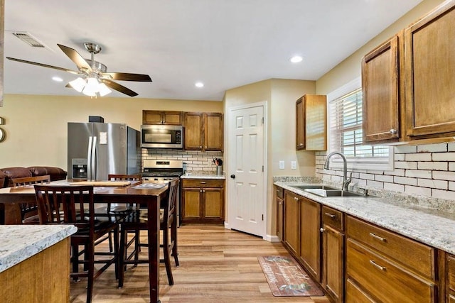 kitchen featuring stainless steel appliances, light stone countertops, sink, and light hardwood / wood-style floors