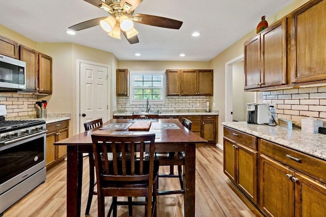 kitchen featuring tasteful backsplash, light stone countertops, appliances with stainless steel finishes, and light hardwood / wood-style floors