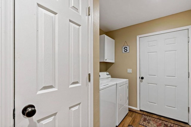 clothes washing area with dark hardwood / wood-style floors, washer and clothes dryer, and cabinets