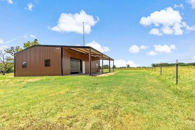 view of yard featuring an outbuilding, a garage, and a rural view