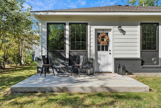 entrance to property featuring a patio area and a yard