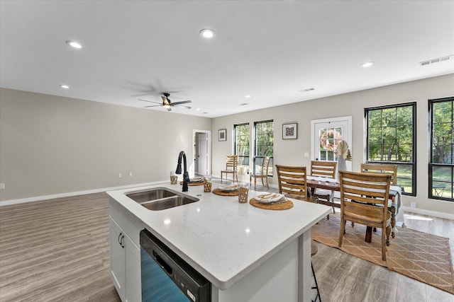 kitchen featuring light wood-type flooring, dishwashing machine, a kitchen island with sink, sink, and white cabinets