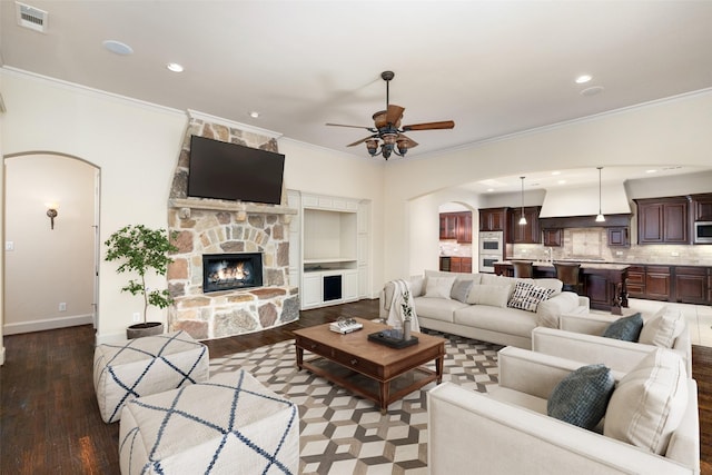 living room featuring a fireplace, ceiling fan, wood-type flooring, and crown molding