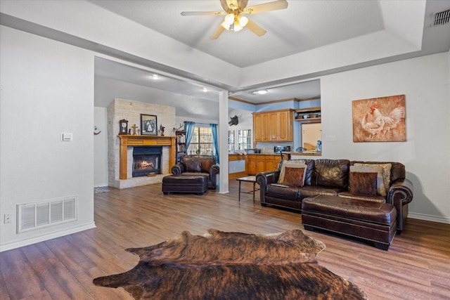 living room with light hardwood / wood-style flooring, ceiling fan, and a tray ceiling