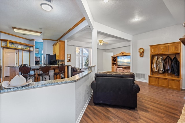 living room featuring ceiling fan, ornamental molding, dark hardwood / wood-style floors, and a textured ceiling