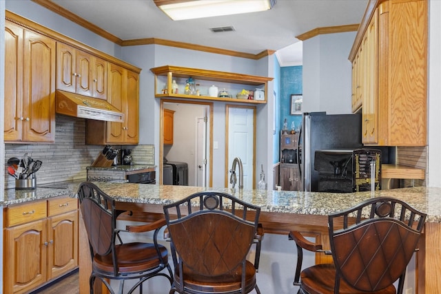 kitchen with backsplash, a kitchen breakfast bar, light stone counters, kitchen peninsula, and custom range hood