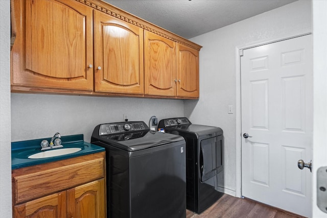 clothes washing area featuring sink, dark wood-type flooring, washing machine and dryer, cabinets, and a textured ceiling