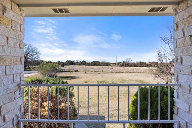 view of yard with a balcony and a rural view