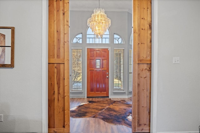 entryway with an inviting chandelier, hardwood / wood-style floors, a wealth of natural light, and ornamental molding