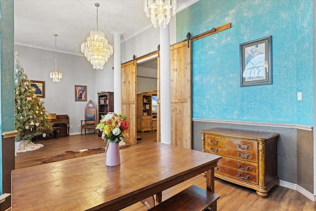 dining area with hardwood / wood-style flooring, ornamental molding, a barn door, and a chandelier