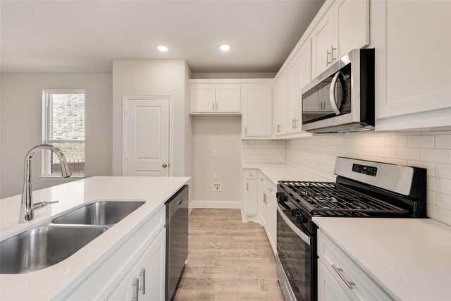 kitchen featuring white cabinetry, sink, stainless steel appliances, and light hardwood / wood-style flooring