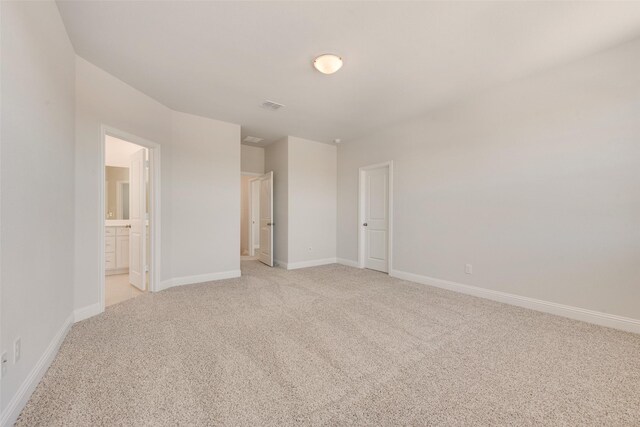 unfurnished bedroom with ensuite bathroom and light colored carpet