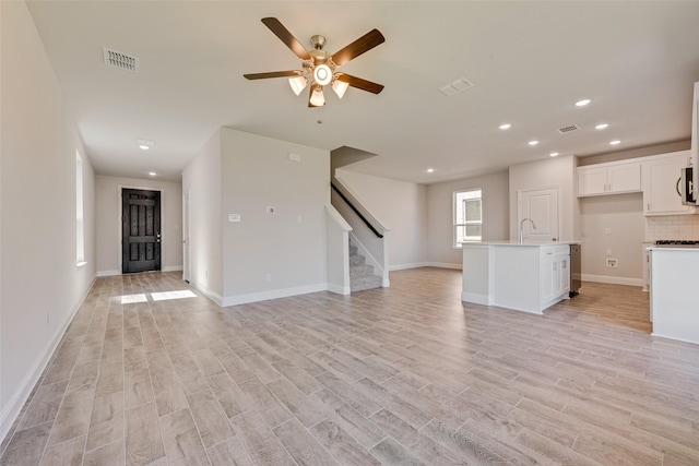 unfurnished living room with ceiling fan, sink, and light hardwood / wood-style floors