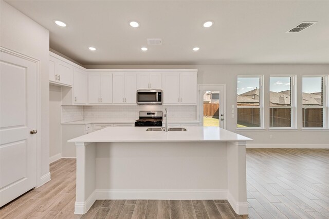 kitchen with stainless steel appliances, white cabinetry, and sink