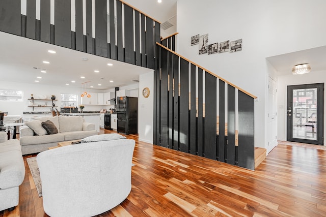 living room with recessed lighting, stairs, light wood-type flooring, and a high ceiling